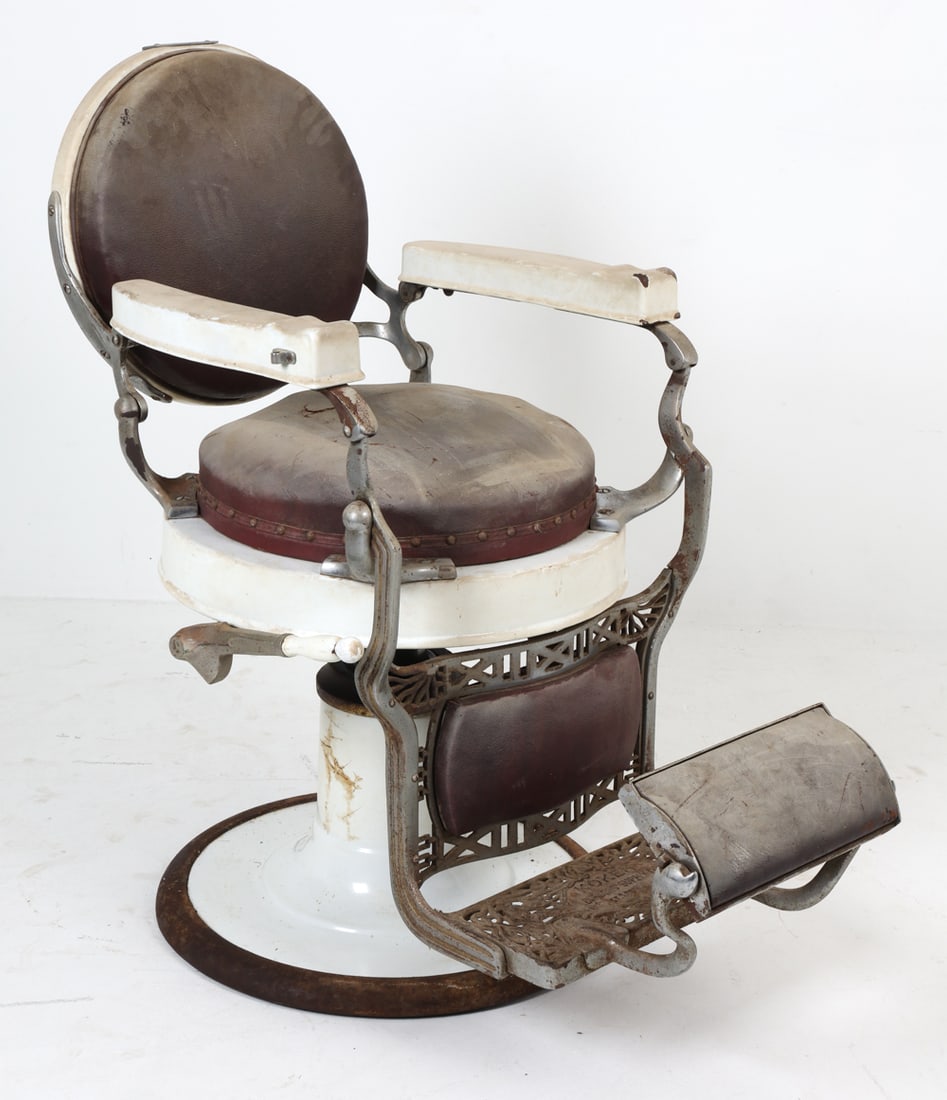 ANTIQUE KOKEN BARBER CHAIR C. 1920S: Hydraulic operated barber chair with porcelain base. Cast iron foot rest and frame. Leather upholstery. Dimensions: H 42" x W 27" x D 39" (lowest) S.H. 27". Condition: Ideal candidate for