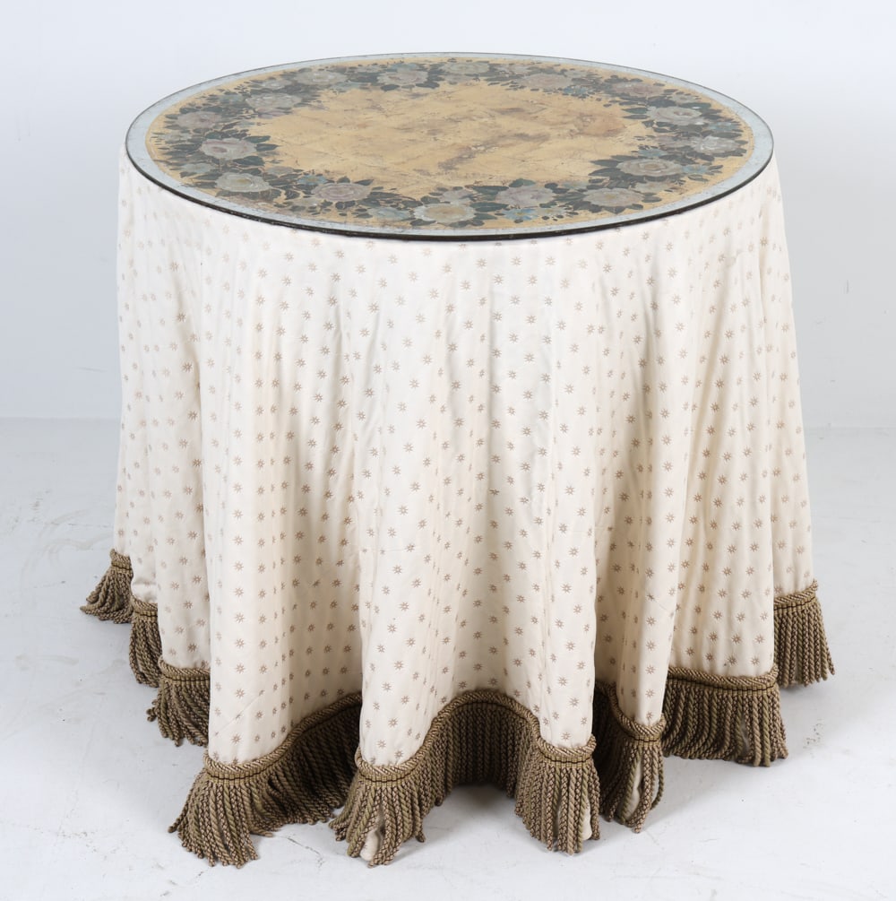 FRENCH REVERSE PAINTED GLASS TOP TABLE: center table with round reverse painted glass top in verre eglomise technique. Includes silk skirt with fringe. 20th century. Dimensions: H 29" x Dia. 30.25". Condition: Minor losses to painted glass