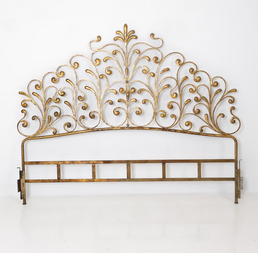 HOLLYWOOD REGENCY GILT IRON HEADBOARD: Decorative wrought iron king size headboard with scrolling foliate motifs and fleur-de-lis crest. Dimensions: H 65" x W 80.5" Condition: Losses to finish, Wear consistent with age and use including