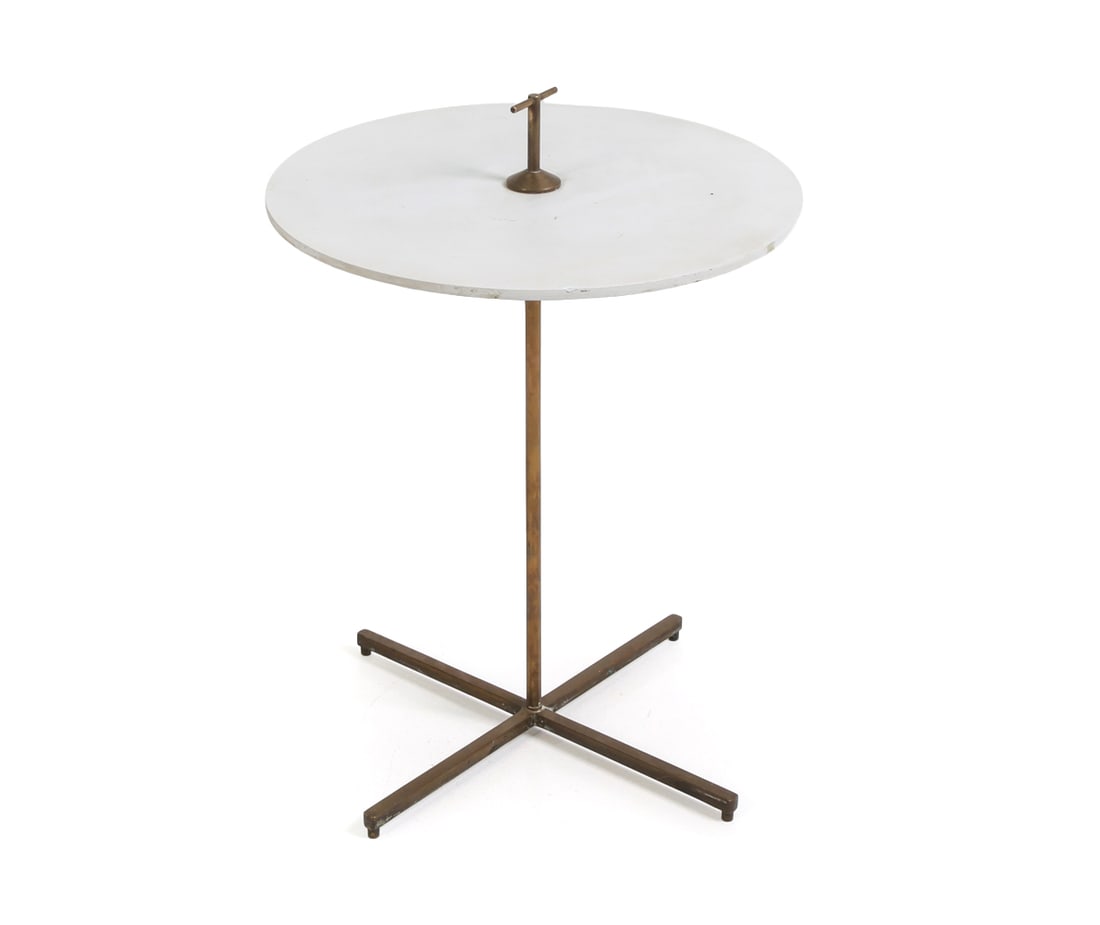 STYLE OF YASHA HEIFETZ SIDE TABLE C. 1960S: Brass tone metal frame with four-point cross base and a painted wooden top. Circa 1960s. Dimensions: H 22" x Dia 16" Condition: Wear consistent with age and use. Patina to brass. Column is slightly lo