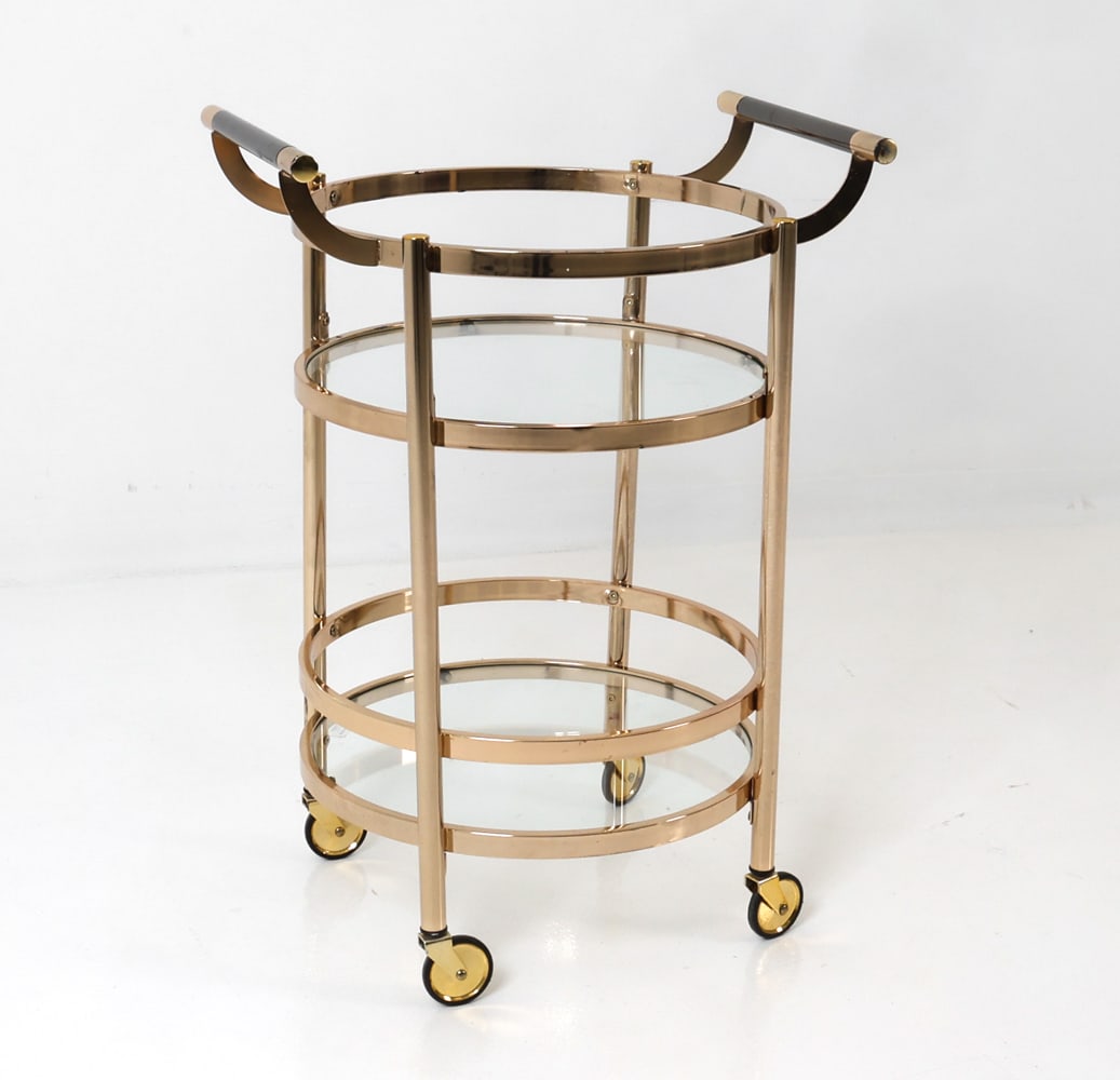 DESIGN GUILD ROLLING 2-TIER SERVING CART: Serving cart on casters featuring two glass tops and handles at top. With sticker for Design Guild. Dimensions: H 33.75" x W 24" x D 19.75" Condition: Wear consistent with age and use including rubs a