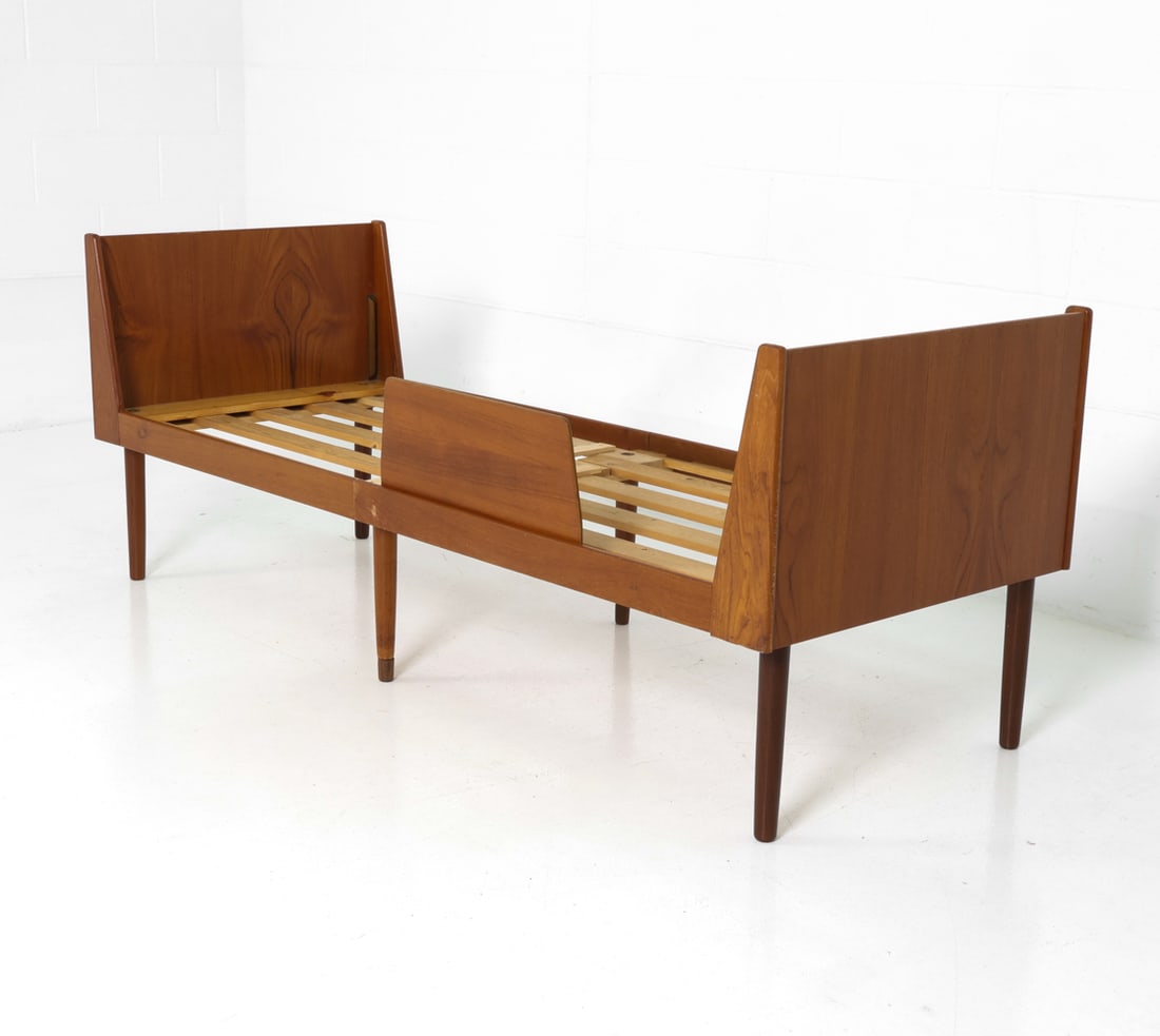 HEVALI FABRIK DANISH TEAK CHILDS BED FRAME C 1960S: Teak frame children bed with wooden slats. Sculpted corners and rounded edges. Tagged to frame. Denmark, circa 1960s. Dimensions: H 27.5" x W 41" x D 27.5" Condition: Rubs and scuffs to frame. Evidenc