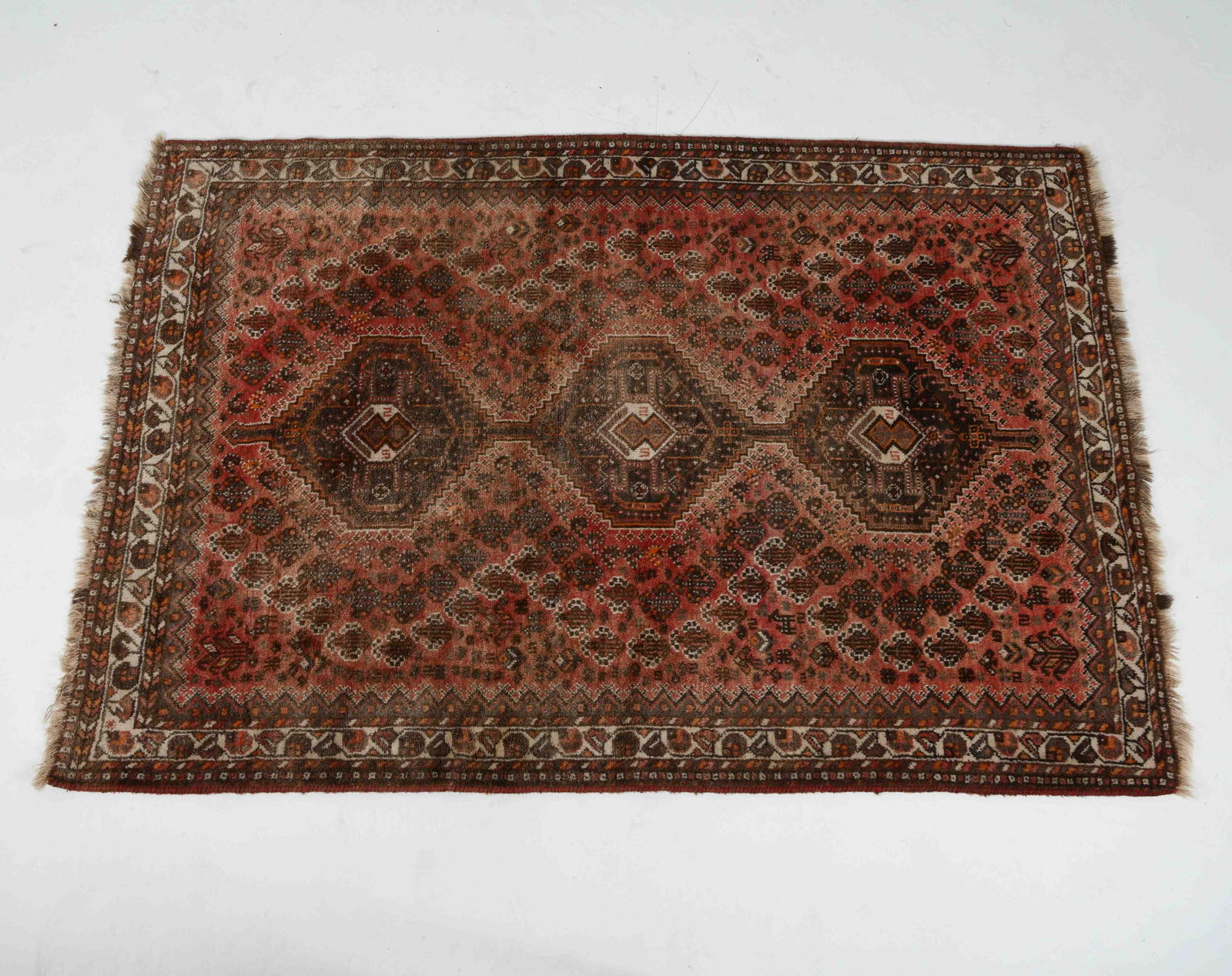 HAND-KNOTTED PERSIAN WOOL RUG: Hand-woven wool rug with beige and red geometric designs. 20th century. Dimensions: L 100" x W 65". Condition: Wear consistent with age and use. Slight sun fading.