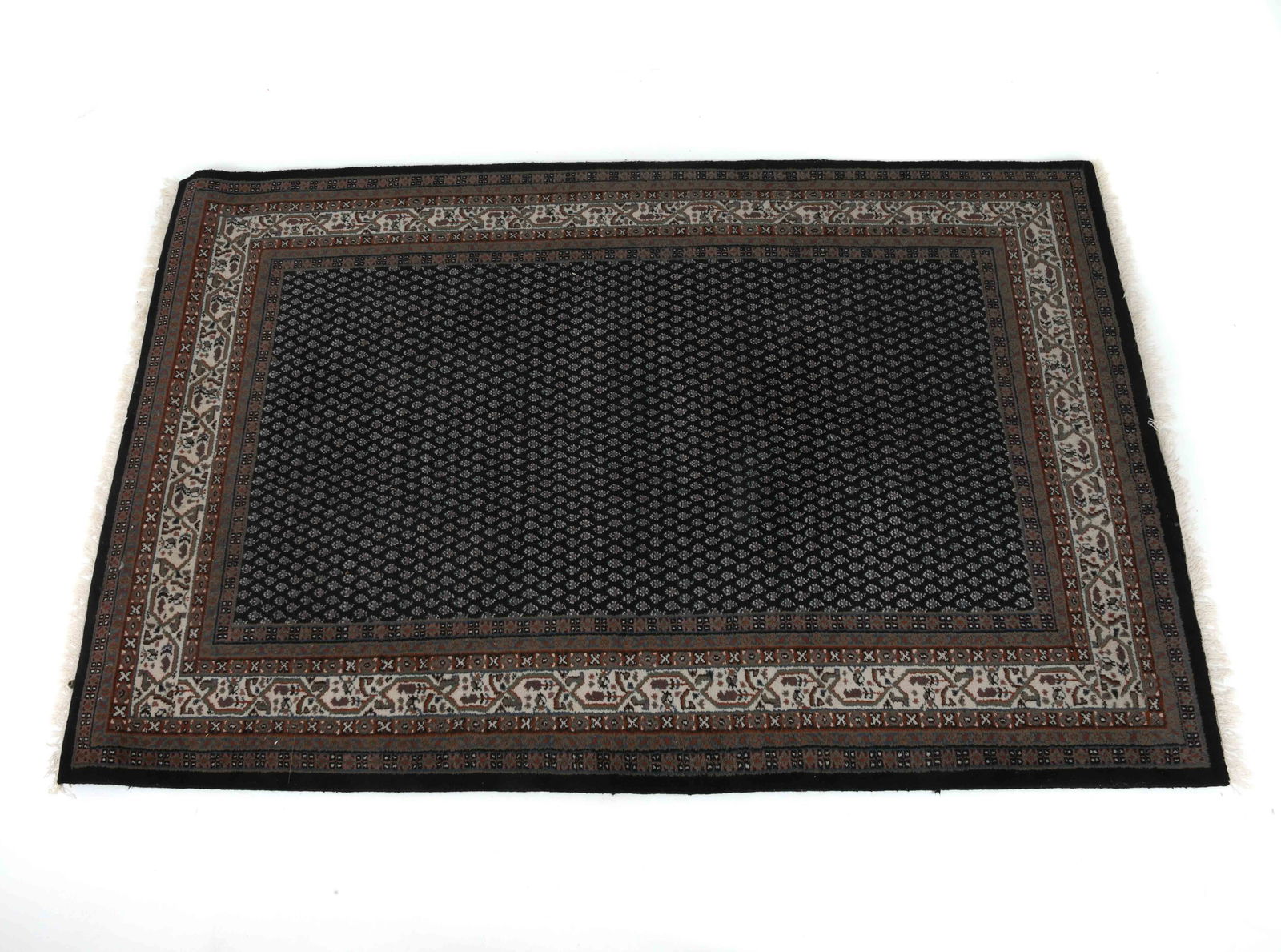 HAND-KNOTTED INDO PERSIAN MIR WOOL RUG: Hand-woven wool rug with black and cream geometric design. 20th century. Dimensions: L 121" x W 77". Condition: Minor staining. Wear consistent with age and use.