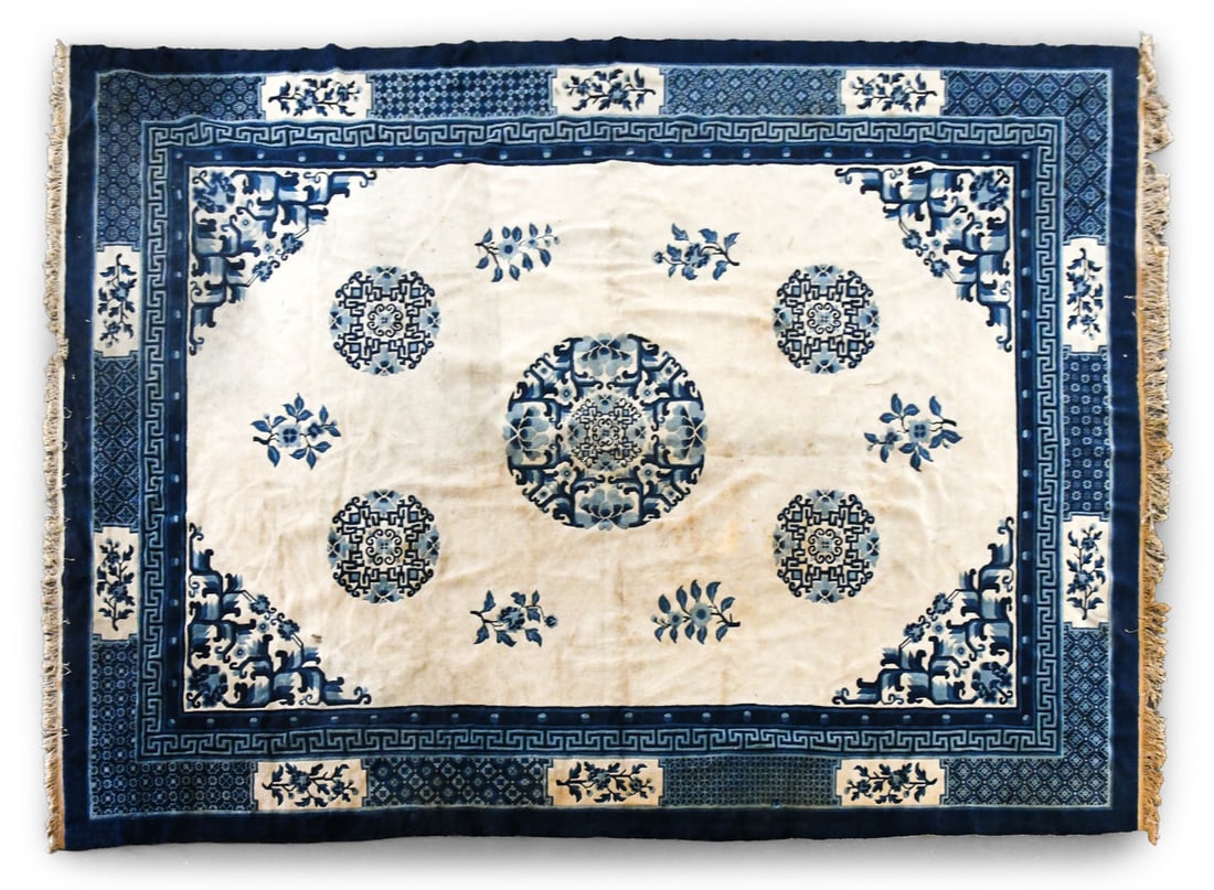 HAND-KNOTTED CHINESE DECO STYLE BLUE & WHITE RUG: Hand-woven wool rug with blue and white floral design. Mid 20th century. Dimensions: L 147" x W 112". Condition: Soiling as shown, needs cleaning, Slight sun fading and discoloration to fringe. Wear