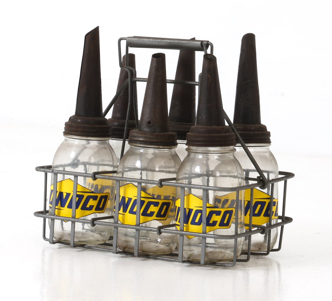 (6) VINTAGE SUNOCO OIL GLASS BOTTLES W/ CARRIER: Sunoco motor oil glass bottles with a metal pouring spout lid, housed in a metal carrier. Yellow Sunoco decals to surface. Marked and dated 1926 to spout. Dimensions: (Bottles) H 13" x Dia 3"