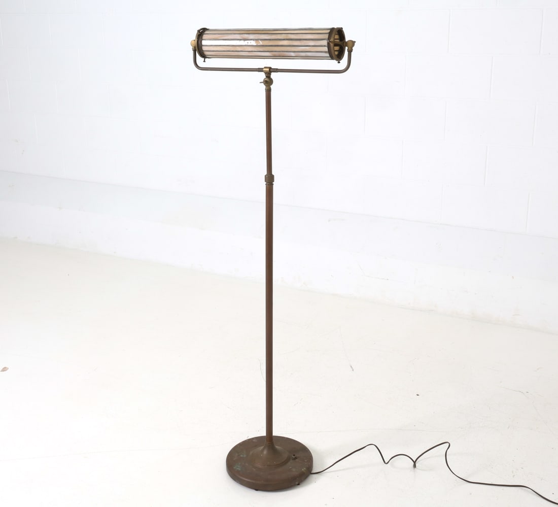 LEADED STAINED GLASS SHADE BRASS FLOOR LAMP: Floor lamp with adjustable base, supporting a cylindrical stained glass shade within a cage frame. Dimensions: H 54" x W 21.75", (shade) D 3.5" Condition: Wiring untested. Oxidation and patina to meta
