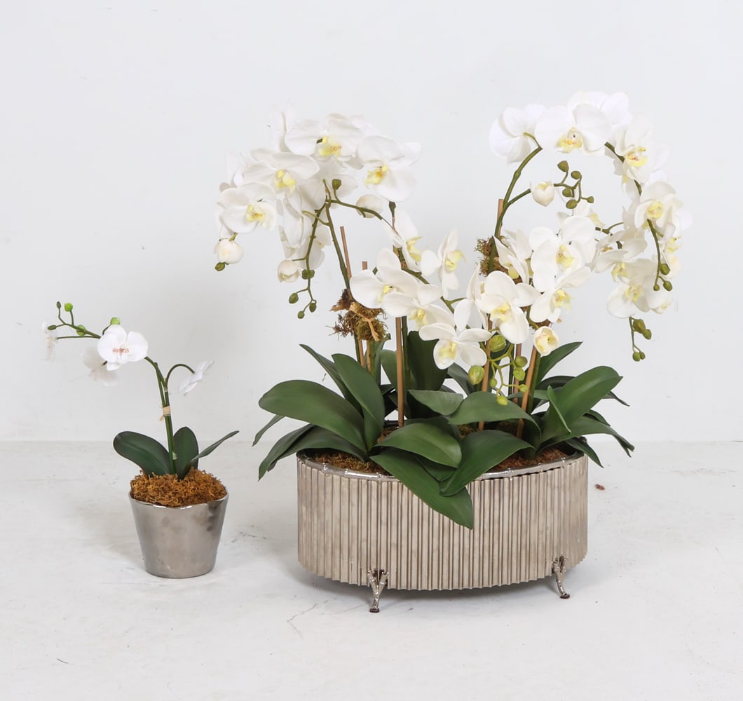 FAUX ORCHID PLANT GROUPING: Includes (2) artificial orchid plants in metal containers. Contemporary. Dimensions: Largest H 26" x W 25" x D 17". Condition: Minor scuffs and dust.