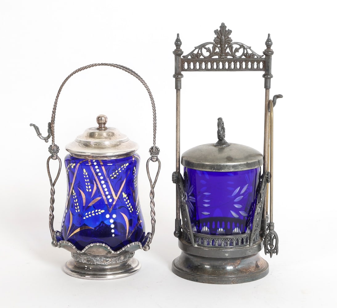 VICTORIAN COBALT GLASS PICKLE CASTOR GROUPING: (2) Pickle castors in silver plate holders. Marked for Simpson, Hall, Miller & Co., and Forbes Silver Co. Includes (1) Pair of tongs. American, circa 1880s. Dimensions: Tallest H 10.5" x Dia. 4.5". To
