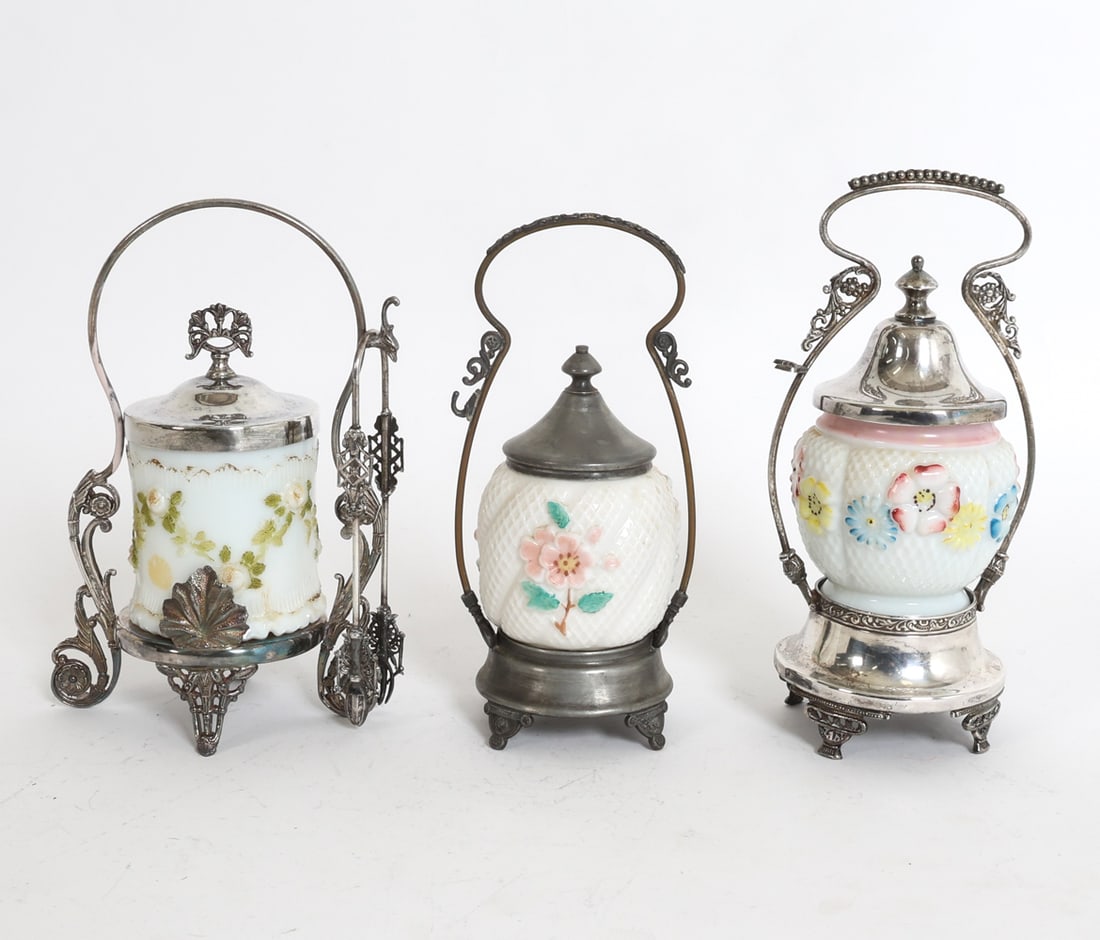 PICKLE CASTOR GROUPING INCL. CONSOLIDATED GLASS: (3) glass pickle castors in silver plate holders. Marked for Brooklyn Silver Plate Co. and Anchor PSC. American, late 1880s. Includes (1) pair of tongs. Dimensions: Tallest H 10" x Dia. 7.25". Tongs