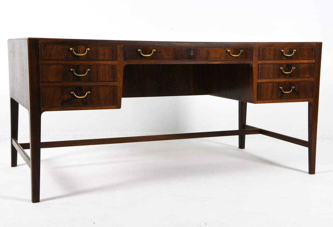 OLE WANSCHER DANISH ROSEWOOD DESK C. 1960S: For A.J. Iversen. Key included. Rosewood writing desk with brass drawer pulls. Drawers to front and back. Apparently untagged. Denmark, circa 1960s. Dimensions: H 29.5" x W 63" x D 31.5". Condition: S