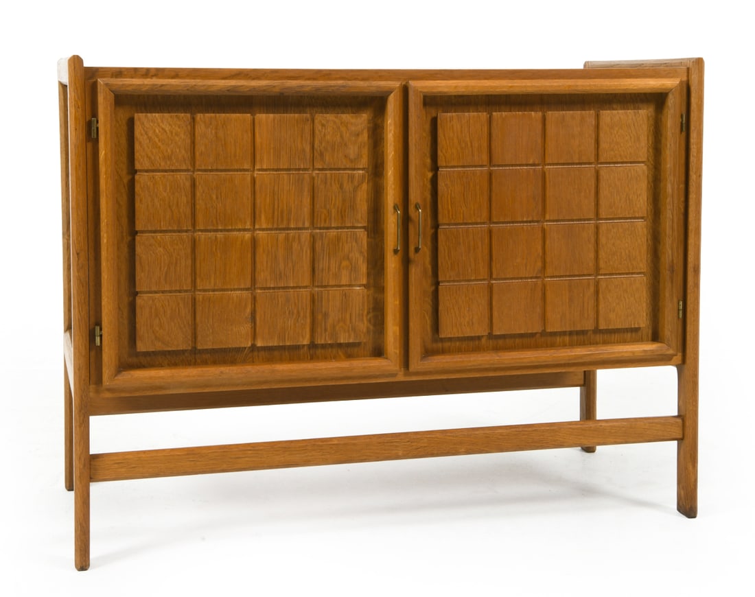 KJAERNULF STYLE DANISH OAK CABINET C. 1960S: Oak cabinet with carved decoration to cabinet doors. Brass pulls. Adjustable shelf. Denmark, circa 1960s. Dimensions: H 28" x W 37" x D 18.5". Condition: Sun fading to top. Wear consistent with age an