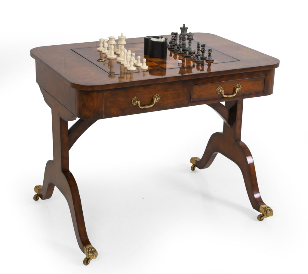 MAITLAND-SMITH REGENCY STYLE GAME TABLE: Game table featuring a burl inlay with a reversible chess and backgammon top with two drawers, sabre legs and brass paw casters. Labeled inside drawer. Dimensions: H 29" x W 36.75" x D 26" Condition: