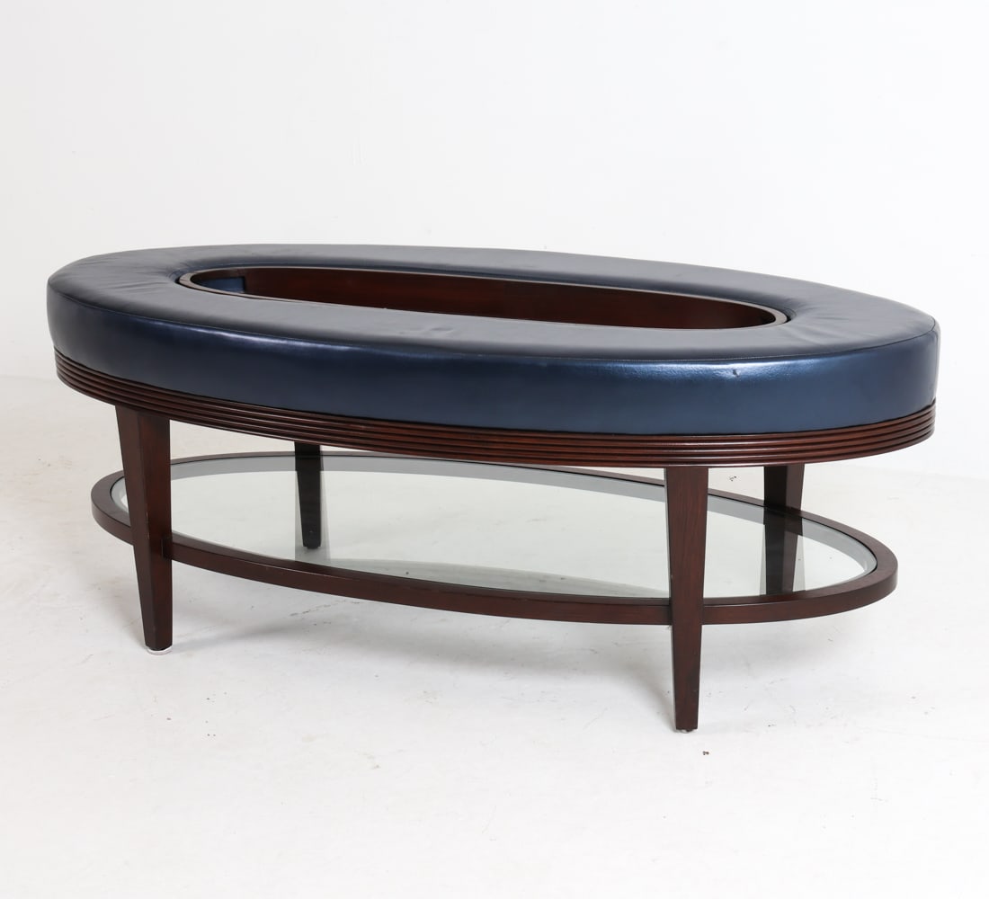 PLUSH HOME "CARLISLE" MAHOGANY COFFEE TABLE: Model Carlisle oval coffee table or ottoman, designed by Nina Petronzia. Mahogany frame with leather upholstery. Removable inset tray and glass lower shelf. Labeled underneath. Contemporary.