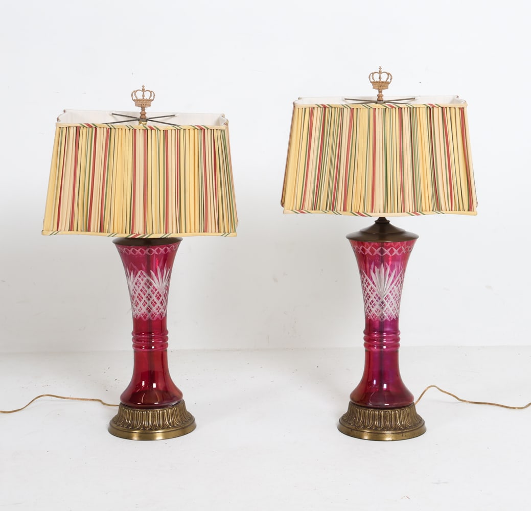 PAIR OF ANTIQUE CRANBERRY GLASS TABLE LAMPS: (2) Table lamps with cranberry cut-to-clear glass featuring etched patterns. Brass bases. Circa 1960s. Dimensions: (w/shade) H 32" X W 17" X D 11". Condition: Showing signs of wear including cracks to