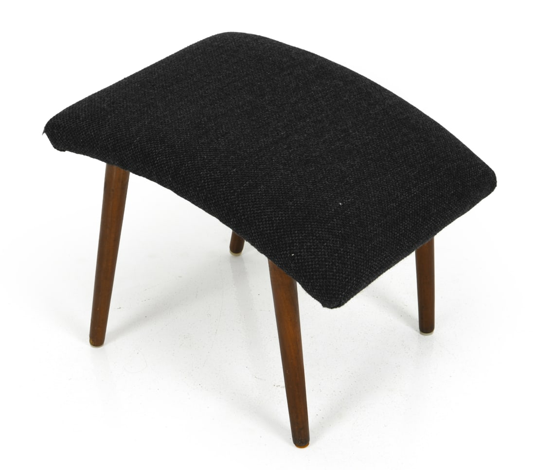 DANISH TEAK OTTOMAN C. 1960S: With dark upholstery and teak legs, featuring curved shape seat. Denmark, circa 1960s. Dimensions: H 14.75" x W 19" x D 15" Condition: Wear consistent with age and use including minor rubs, scuffs to