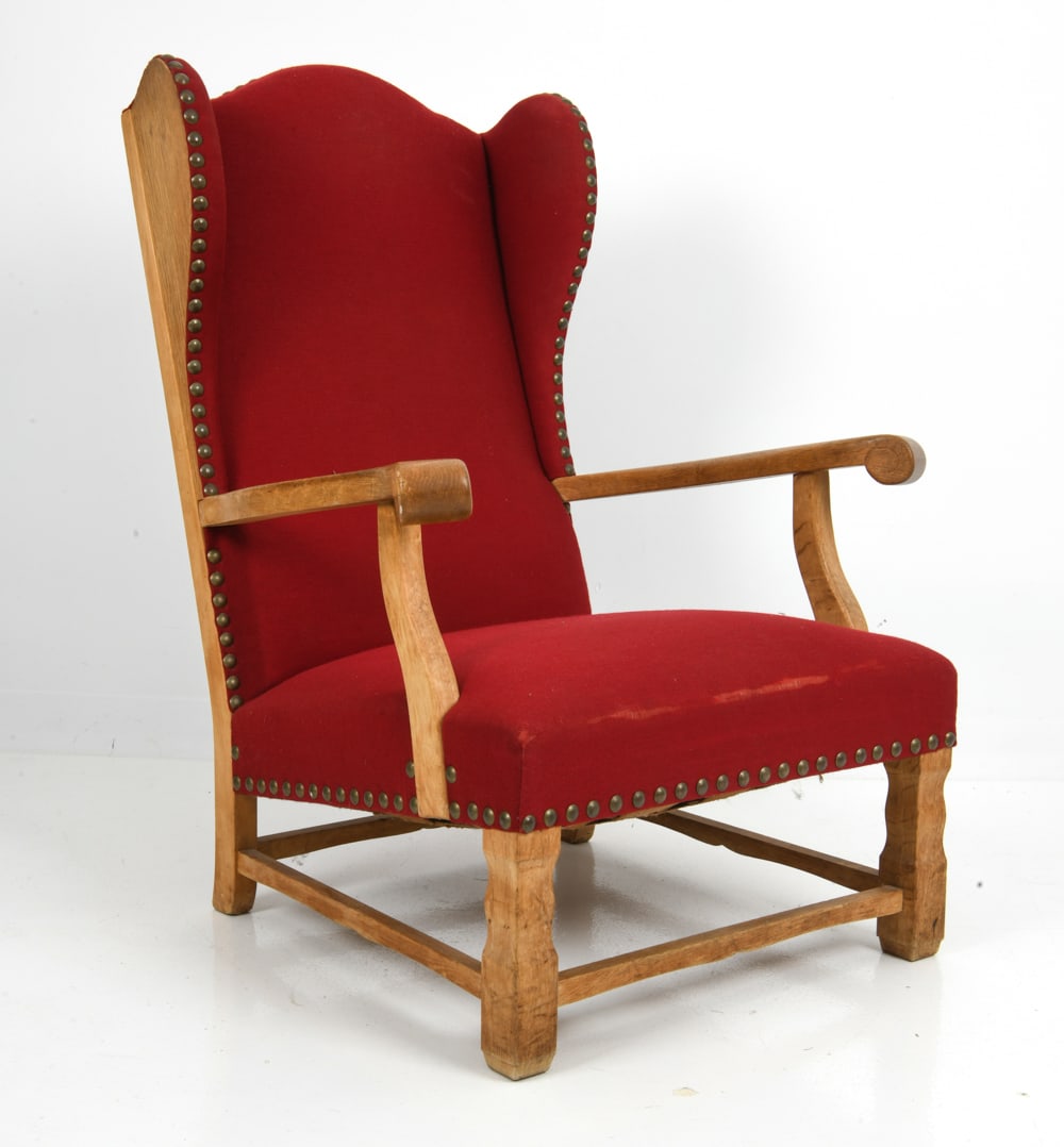STYLE OF HENNINGSEN DANISH OAK WINGBACK CHAIR: Danish lounge armchair in oak, featuring red upholstery and nailhead trim. Denmark, 1960s. Dimensions: H 40" x W 30" x D 33" x SH 16" Condition: Wear consistent with age and use. Scuffs, fading to woo