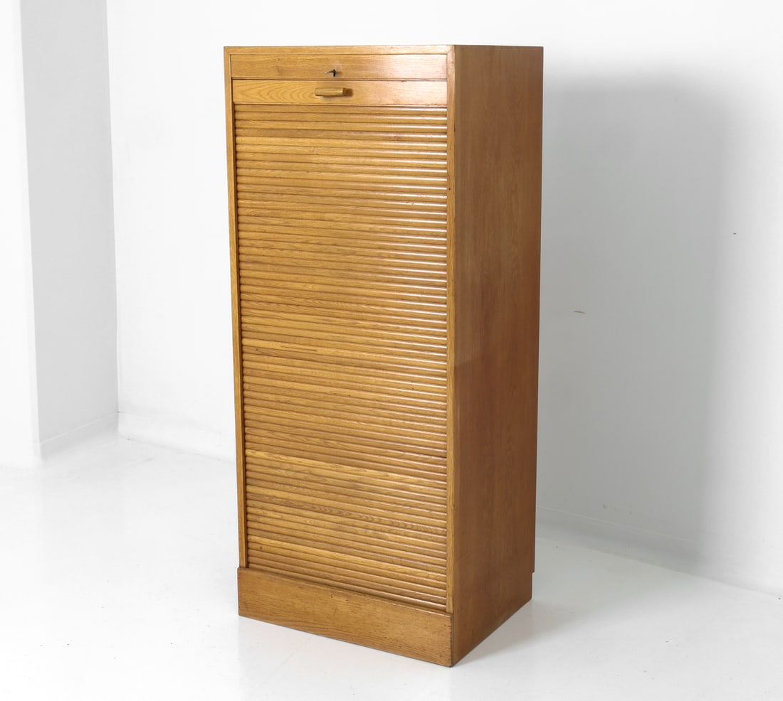 DANISH OAK TAMBOUR CABINET C. 1960S: Key included. Tambour filing cabinet with multiple drawers inside the unit. In oak. Danish, circa 1960's. Dimensions: H 60" x W 26" x D 20" Condition: Wear consistent with age and use. Nicks, scuffs,