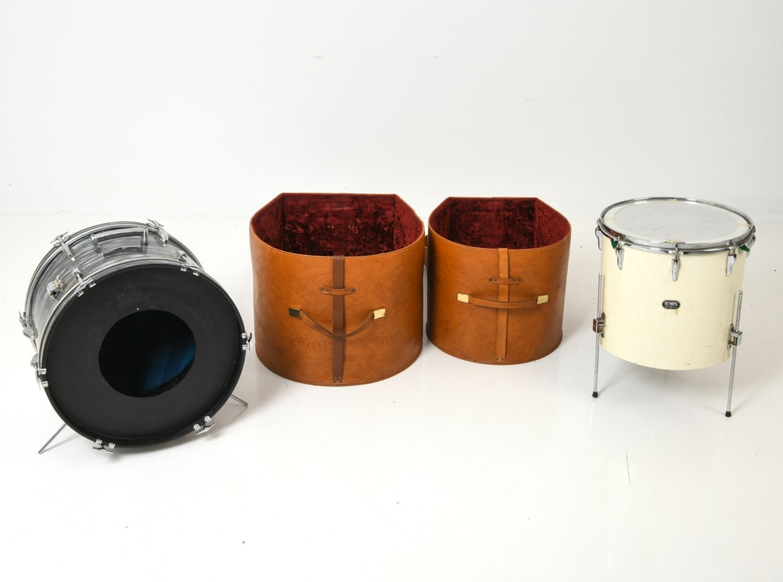 (2) OLYMPIC DRUMS W LEATHER CASES C. 1970S: Two drums, including an Olympic floor tome on tripod legs, with leather cases. One with Remo drum head replacement and internal foam possibly for muffling. Marked to exterior. England, circa 1970s.