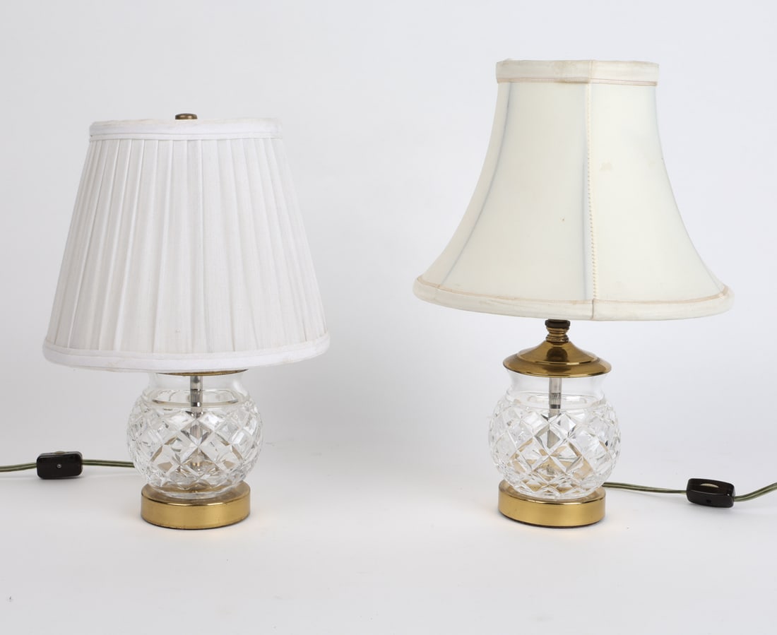 PAIR OF CUT GLASS TABLE LAMPS: Pair of table lamps with crystal bodies and brass fittings. Dimensions: H 11.5" x Dia. Base 3.75". Condition: Wiring untested. Sockets are bent slightly. Few tears to shades. Wear consistent with age