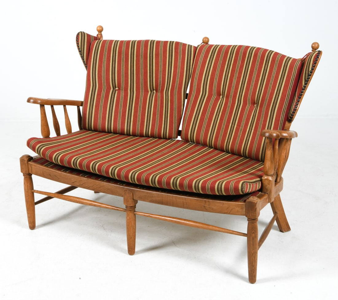 KJAERNULF STYLE DANISH OAK WINGBACK LOVESEAT 1970S: Ear-flap two-seater sofa or settee in oak frame with striped upholstered cushions. Denmark, circa 1970s. Dimensions: H 34.25" x W 48" x D 27.75" x SH 16". Condition: Minor rubs and scuffs to legs and