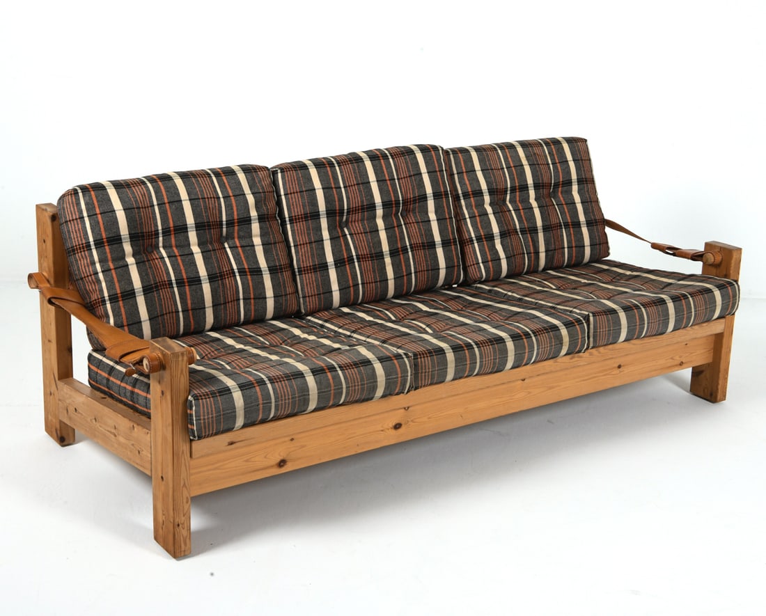 RAINER DAUMILLER STYLE DANISH PINE SOFA C. 1970S: Pine frame with leather straps for arms. Wool plaid cushions. Denmark, circa 1970s. Dimensions: H 33" x W 73" x D 33" x SH 17". Condition: Slight sun fading to frame. Scuffs and rubs to wood and leath