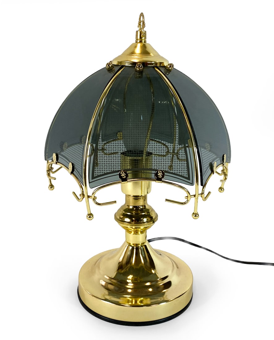 SCANDINAVIAN BRASS & GLASS TABLE LAMP C. 1970S: Brass table lamp with smokey glass panels to shade. 'SS' marked to brass clips on shade. Scandinavian, circa 1970s. Dimensions: H 14.5" x Dia. 9". Condition: Wiring untested, European plug. Minor scuf