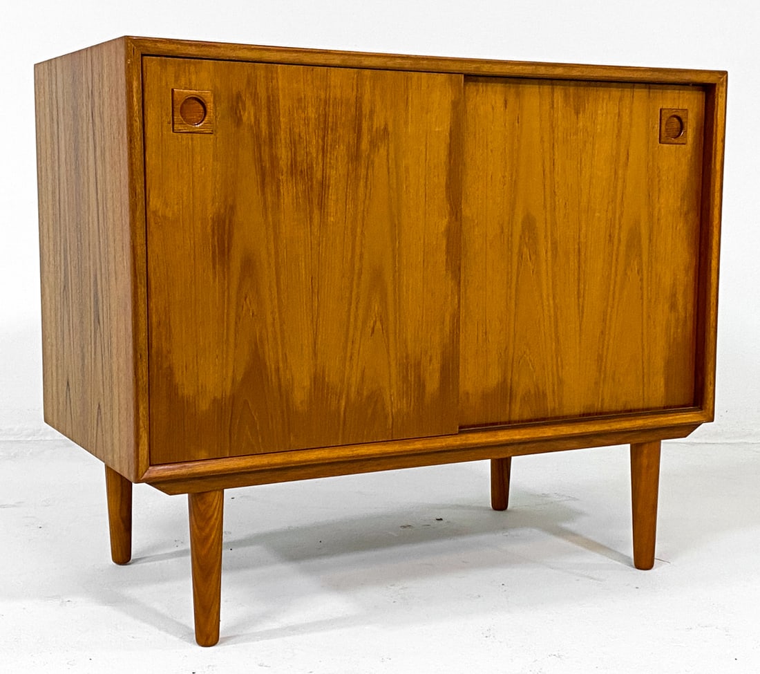 DANISH TEAK CABINET C. 1960S: Adjustable shelves. Round molded inset cabinet door pulls. Denmark, circa 1960s. Dimensions: H 29.25" x W 35.75" x D 17.75". Condition: uneven finish color to doors as shown. Few light scratches to to