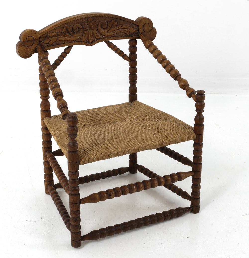DUTCH OAK BOBBIN-TURNED ARMCHAIR C. 1920S: Dutch art deco bobbin chair in oak frame with woven rush seating. Spool-turned wooden legs, stretchers, and arms with carved details. Netherlands, circa 1920s. Dimensions: H 29" x W 22" x D 16" x SH 1