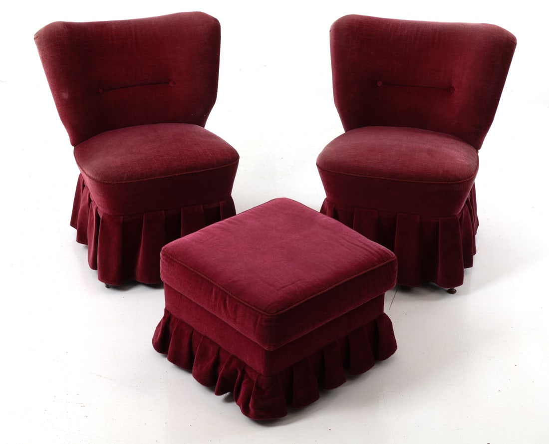 PAIR OF GERMAN VELVET SLIPPER CHAIRS W OTTOMAN: Two cocktail chairs with footstool in burgundy velvet upholstery with skirts detail to base. Germany, circa 1960s. Dimensions: H 30" x W 26.5" x D 28" x Sh 17" (Ottoman) H 14.25" x W 19.5" x D 19.5" C