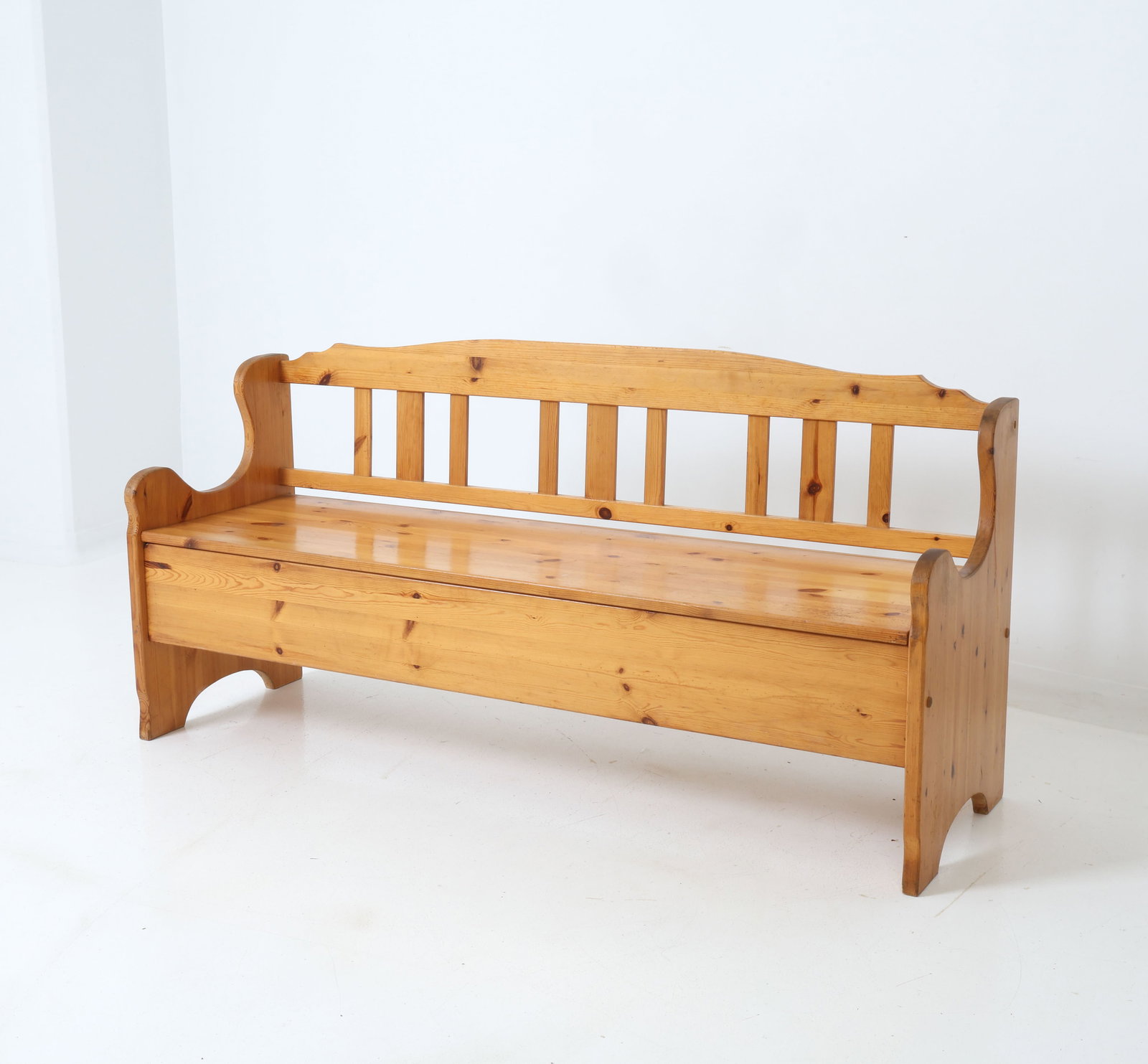 TRADETS MOBLER SWEDISH PINE BENCH C. 1950S: Swedish sofa (Kokssoffa in Swedish) in pine. Wavy top rail and vertical spindle to backrest. Hinged seat that lifts to reveal a storage compartment. Tagged to underside of seat lid. Sweden, circa 1950