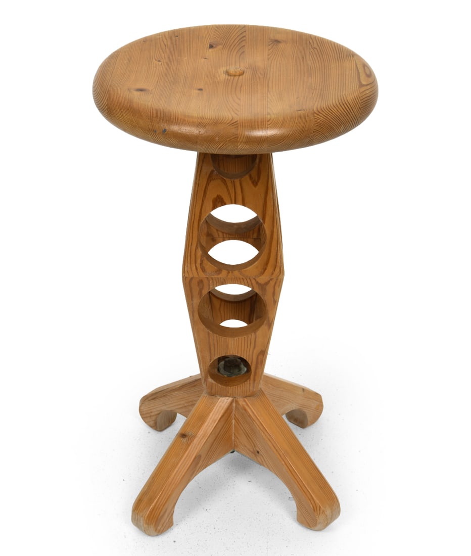 MID-CENTURY SCANDINAVIAN PINE STOOL C. 1970S: Pine stool featuring holes through the sides as part of the unique design and X-form legs. Unmarked. Dimensions: Height 21" x Diameter 11.75" Condition: Fading to finish. Scuffs and dings to surface a