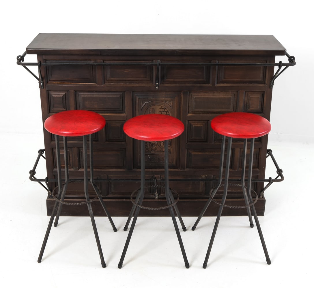 DUTCH OAK & IRON BAR W (3) BAR STOOLS: Brutalist oak bar with ornate carved relief on the front and cast iron bracket on top and bottom. Bar stools in iron frame with red faux leather upholstered seats. Netherlands, circa 1960s. Dimensions