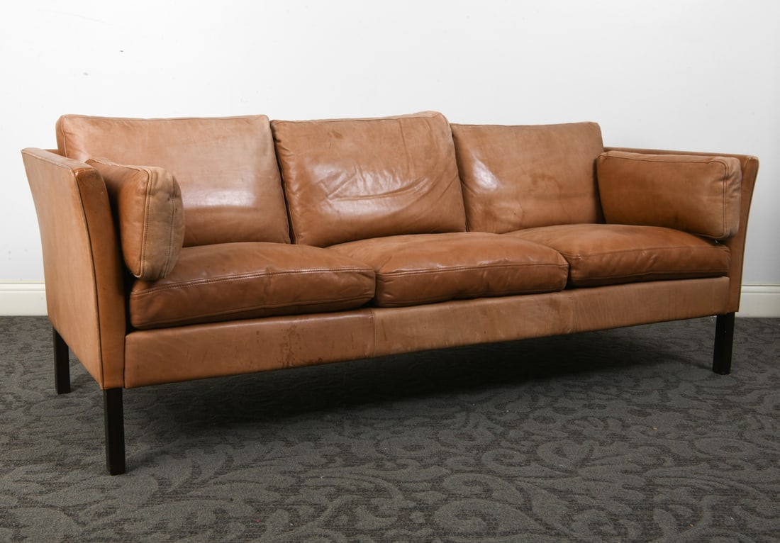 MOGENS HANSEN STYLE DANISH LEATHER SOFA 1970S: Cognac leather upholstery with beech legs. Denmark, circa 1970s. Dimensions: H 26.5" x W 76.5" x D 30" x SH 16". Condition: Fading and discolored spots to leather. Small tear to fabric lining under
