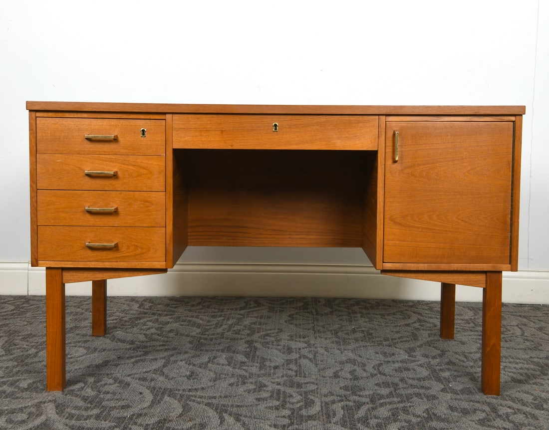 DANISH TEAK WRITING DESK C. 1960S: Key included. Teak writing desk with brass pulls to drawers and cabinet. Denmark, circa 1960s. Dimensions: H 29" x W 48" x D 25". Condition: Few thin surface scratches. Wear consistent with age and us