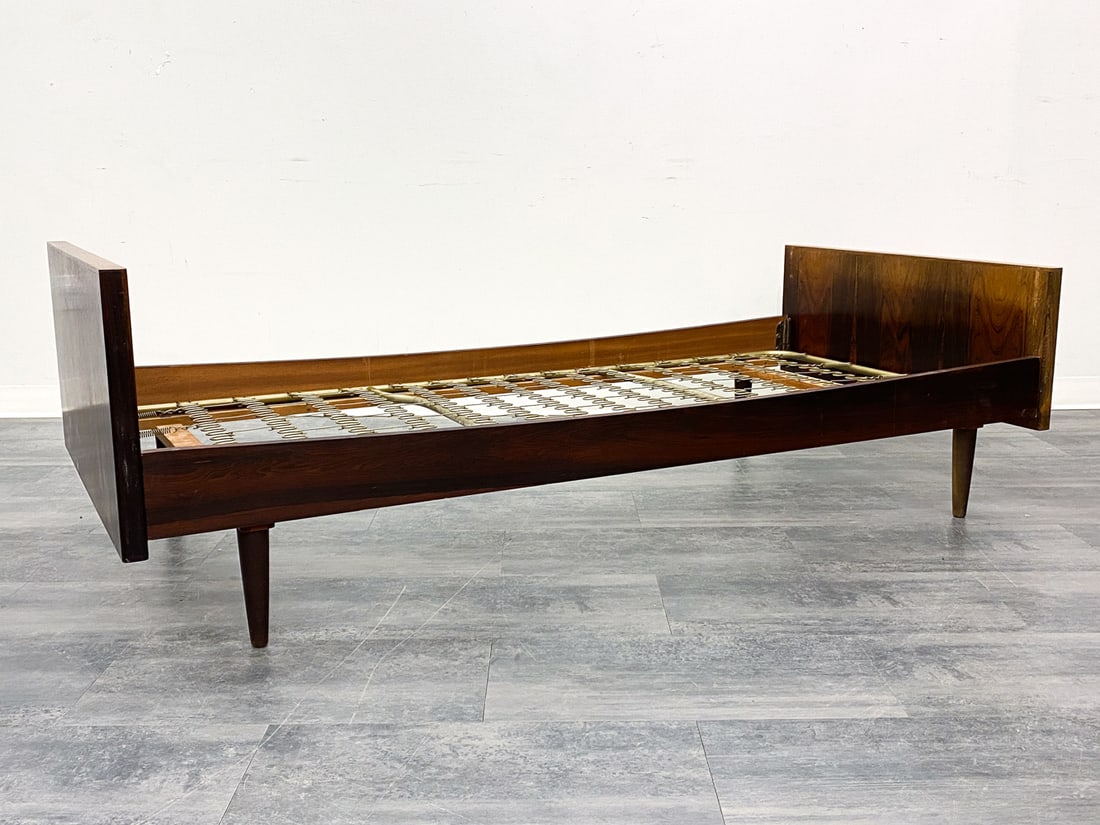 HANS WEGNER STYLE ROSEWOOD TWIN BED FRAME C. 1960S: Rosewood bed frame for twin sized mattress. Metal springs. Denmark, circa 1960s. Dimensions: H 24.5" x W 36.25" x D 78.5". Condition: Sun fading to headboard. Scuffs, scratches, and dings. Wear consis