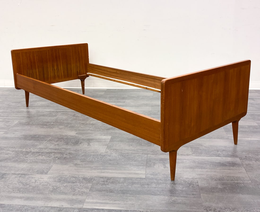 HANS WEGNER STYLE TEAK TWIN BED FRAME C. 1960S: Teak bed frame designed to fit a narrow twin sized mattress. Denmark, circa 1960s. Dimensions: H 24" x W 36" x D 81". Condition: No slats. Scuffs, scratches, and dings. Few white paint marks. Other si