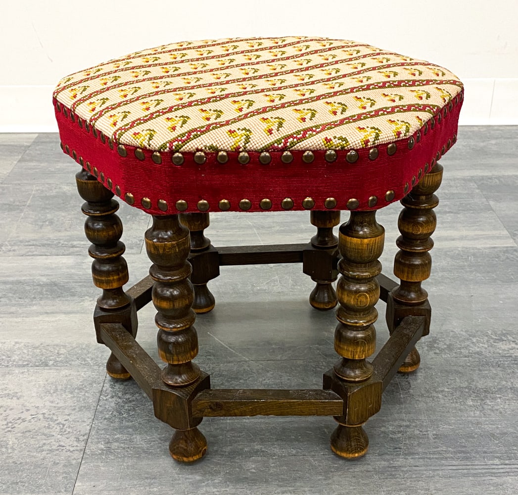 DANISH OAK NEEDLEWORK OTTOMAN FOOTSTOOL C. 1960S: Turned oak legs with needlework wool upholstered top. Brass tacks accents. Denmark, circa 1960s. Dimensions: H 14.5" x Dia. 16.5". Condition: Scuffs and dings to legs, wear consistent with age and use