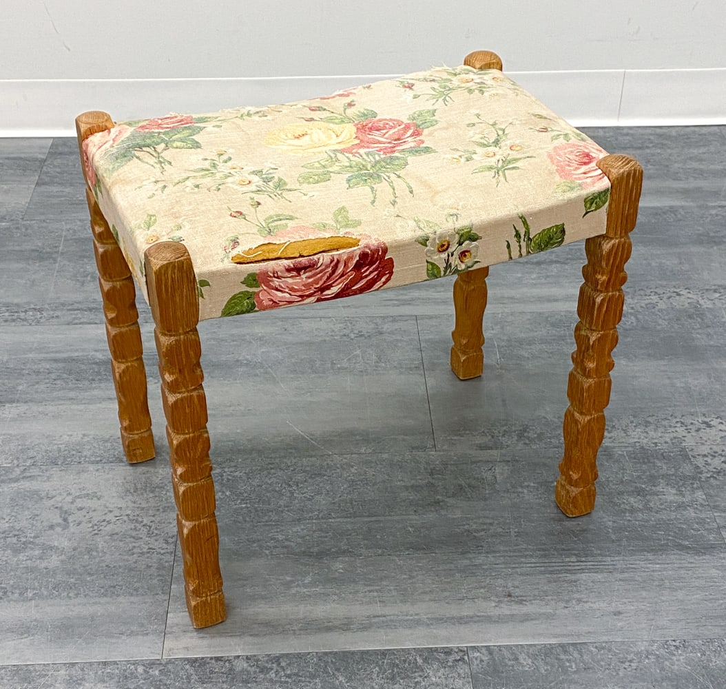 HENNING KJAERNULF STYLE OAK OTTOMAN STOOL 1970S: Ottoman stool with turned oak legs and floral fabric upholstery. Denmark, circa 1970s. Dimensions: H 17" x W 18.75" x D 12.75". Condition: Tears to fabric, fading, and discoloration. Wear consistent