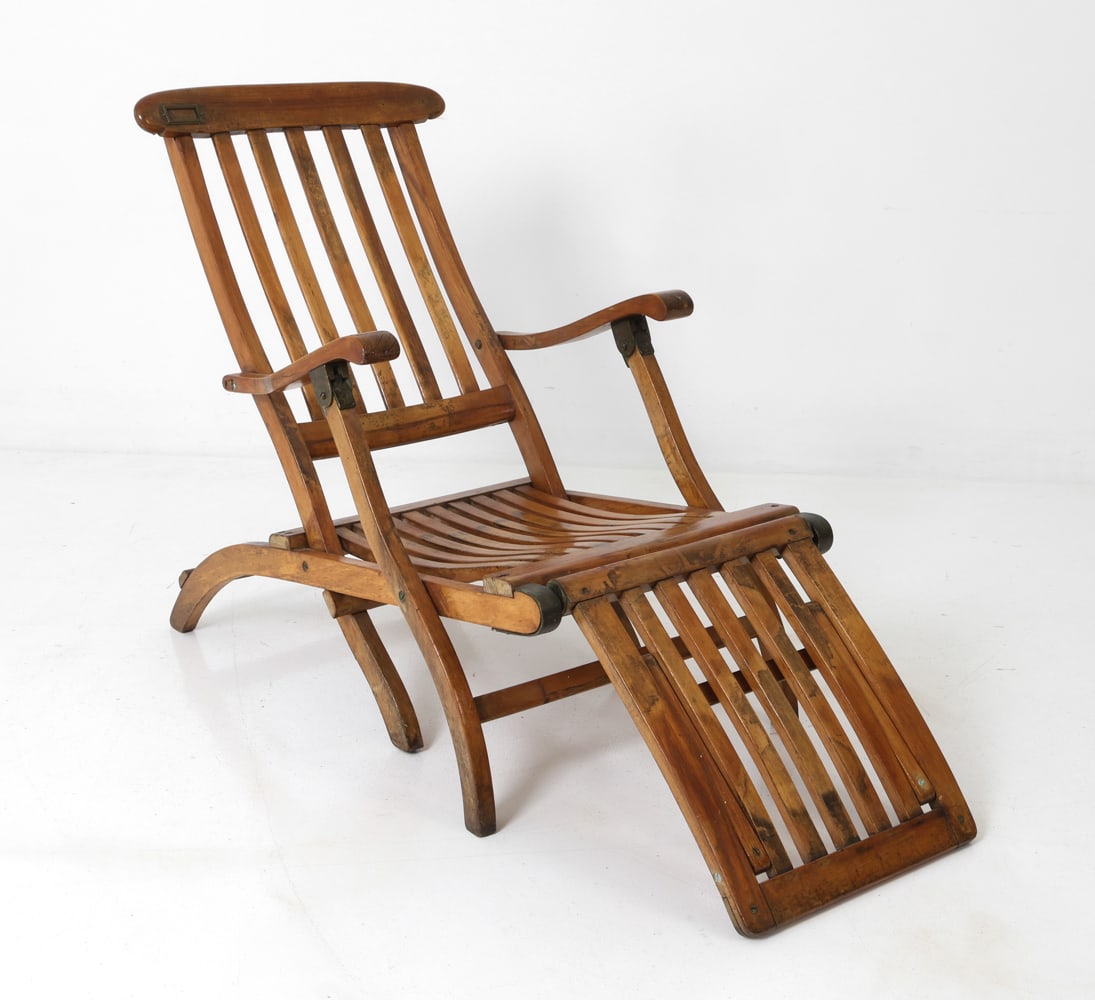 STYLE OF RMS QUEEN MARY OAK FOLDING DECK CHAIR: Deck chair in multi-hinged folding oak frame. Curved armrests and fold-out footrest. 20th century. Dimensions: H 34.5" x W 23" x D 53.5" x SH 14" Condition: Fading, discoloration, rubs, scuffs to fram