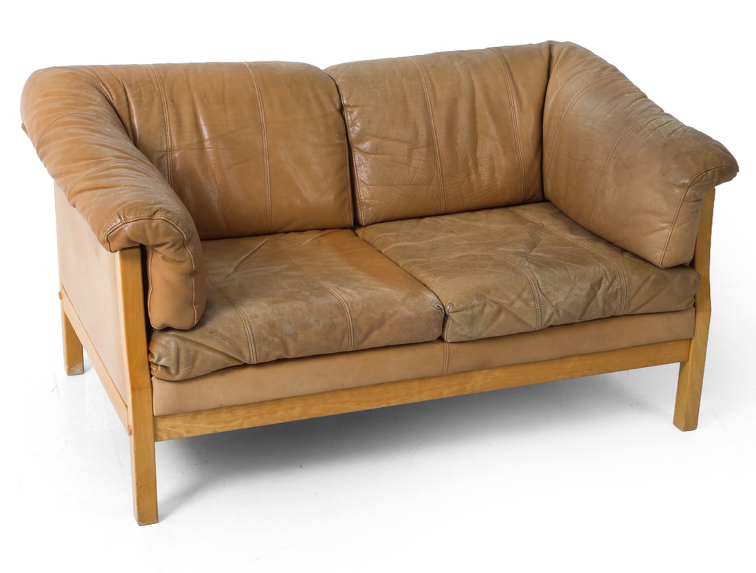 STOUBY DANISH LEATHER LOVESEAT: Tan leather sofa with beech frame. Branded to fabric lining under cushions. Denmark. Dimensions: H 30" x W 52" x D 32.5" x SH 14.75". Condition: Scuffs and scratches to leather, slight fading and few 