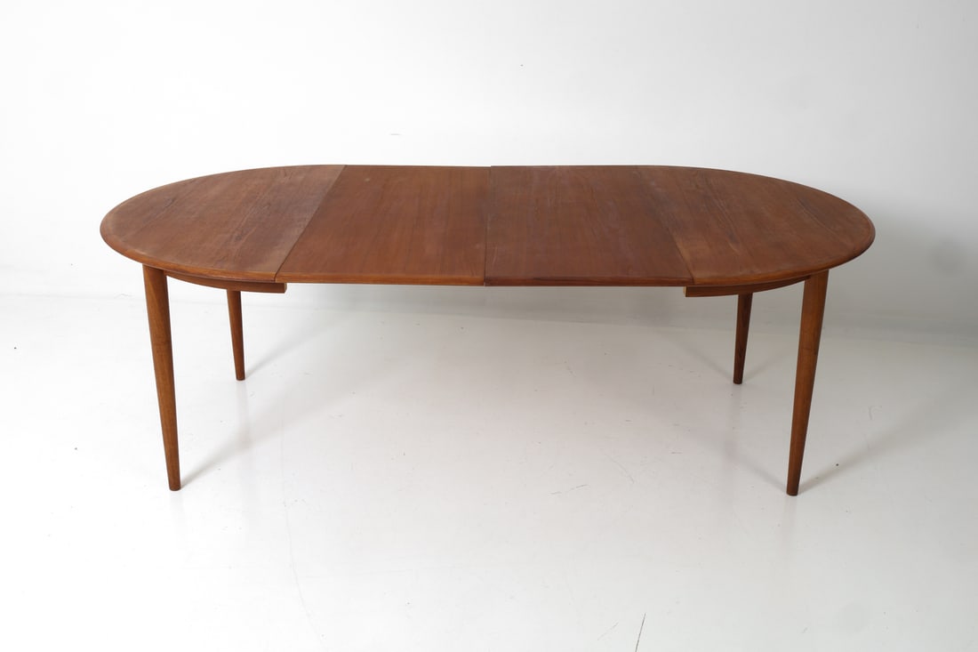 STYLE OF NILS JONSSON TEAK DINING TABLE C. 1970S: Two leaves included. Swedish extending dining table in teak. Tapered legs and circular top. Dimensions: H 29" x Dia 46.5" (Leaf) W 19.5" Condition: Wear consistent with age and use. Scuffs, fading and