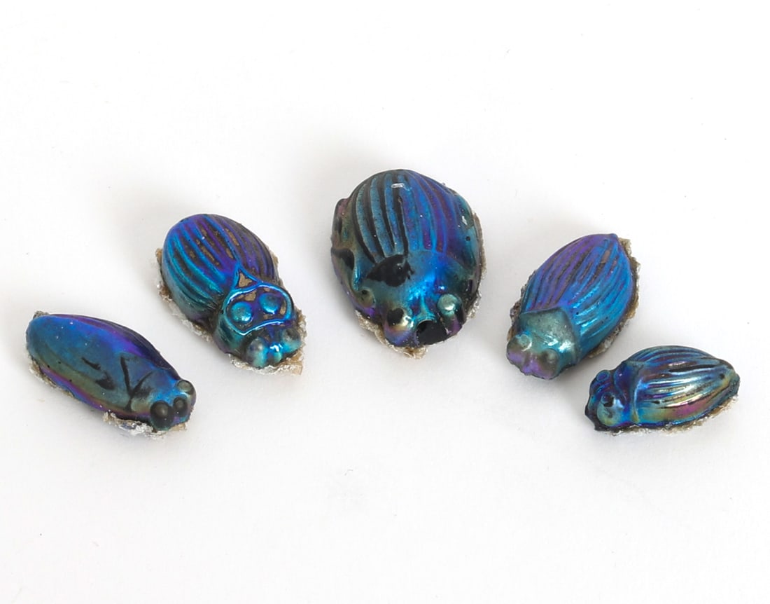 TIFFANY & CO. FAVRILE ART GLASS SCARAB GROUPING: Grouping of (5) iridescent glass scarabs, used as decorative accents for jewelry or larger works. Apparently unmarked. Dimensions: Largest H 1". Condition: Excessive glue like material to underside of