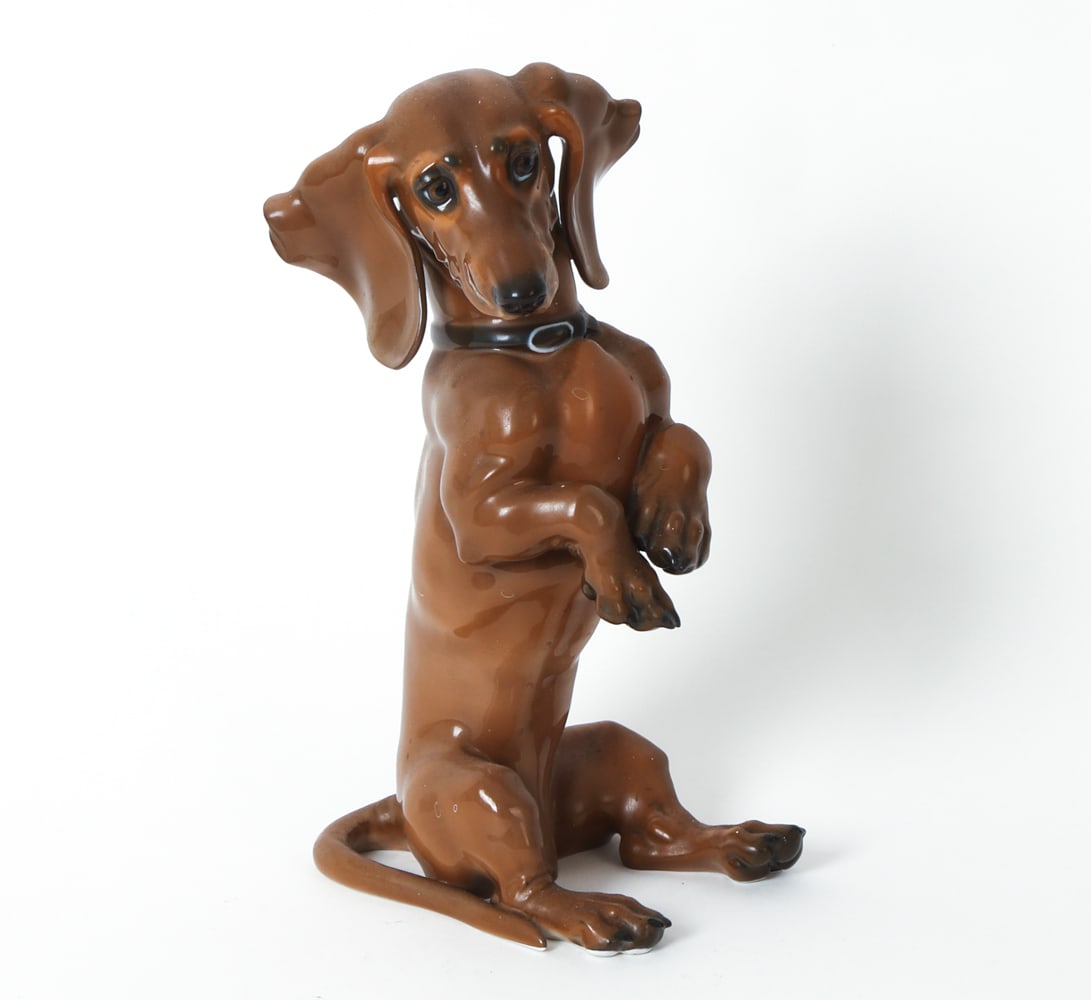 THEODOR KARNER ROSENTHAL PORCELAIN DOG FIGURE: Marked underneath. Designed by Theodore Karner for Rosenthal. Porcelain ceramic figure of a Dachshund puppy. Model #1129. Circa 1930s. Dimensions: H 10" x W 4.25" x D 5.25" Condition: Light surface ma