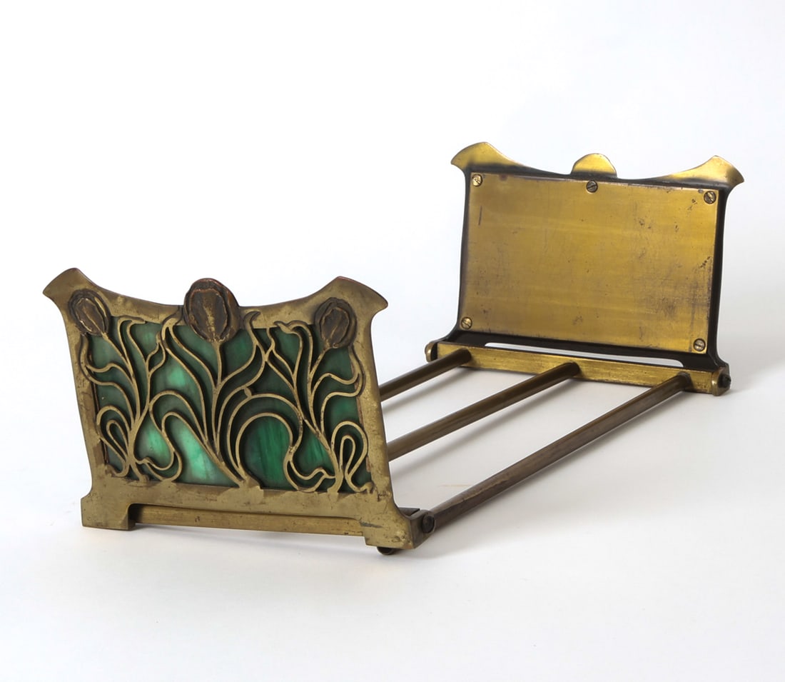 ATTR. BRADLEY HUBBARD BRASS & GLASS LETTER RACK: Expandable brass letter rack with green slag glass to either end. Apparently unmarked. Circa 1920s. Dimensions: H 4.5" x W 13.75" - 25" x D 6.75". Condition: Scuffs, scratches, and rubs to brass. Ligh