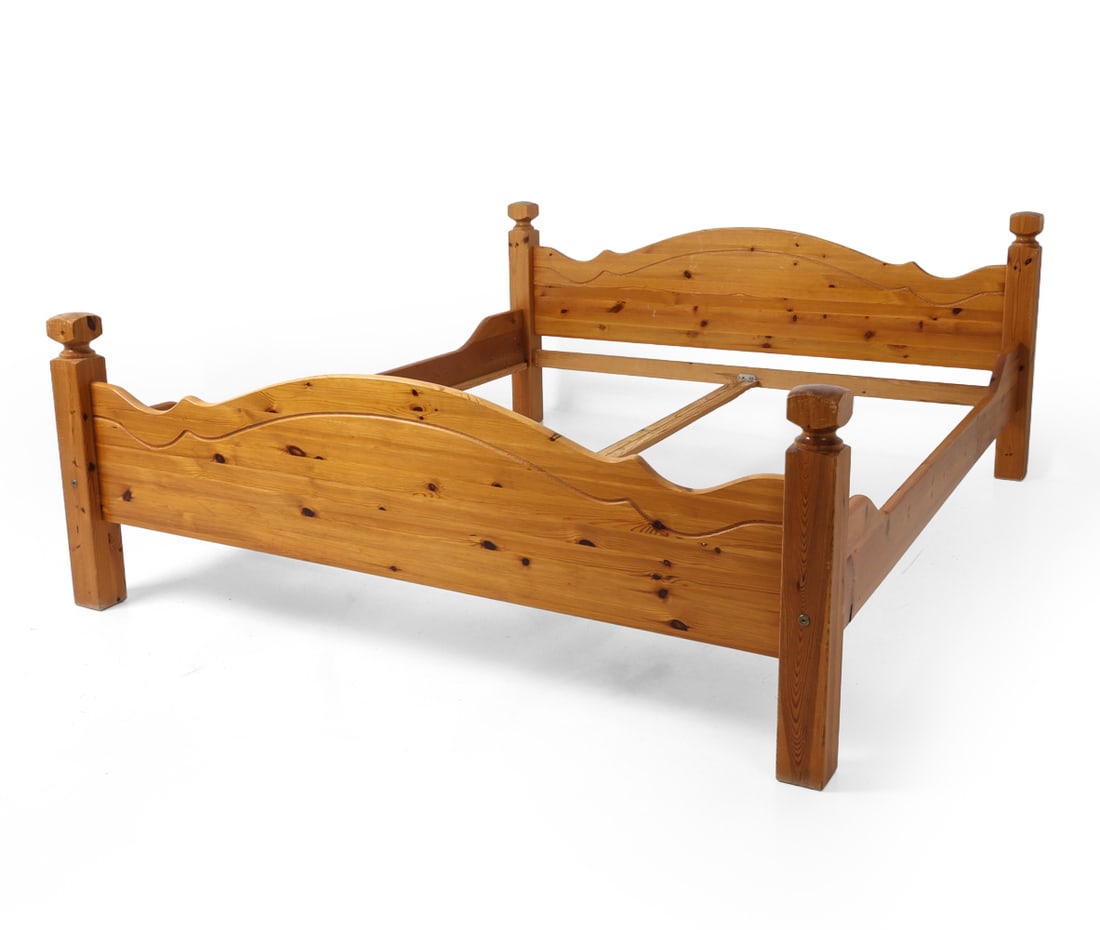 SCANDINAVIAN PINE KING BED FRAME C. 1970S: Pine bed frame with turned bed posts and curved and sculpted details. Apparently unmarked. Dimensions: H 31" x W 72" x D 85". Condition: Lacking slats. Faint scuffs and scratches. Wear consistent with
