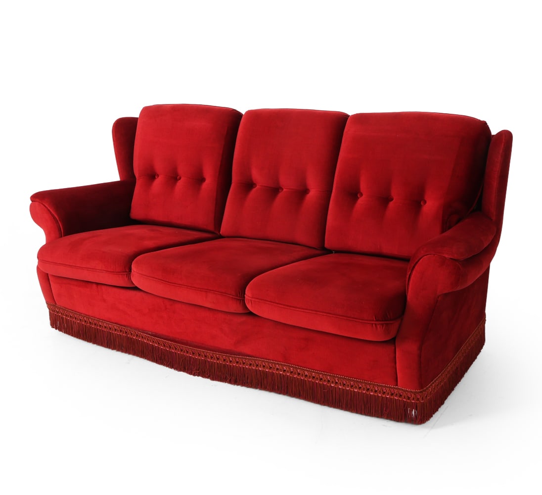 FRITS HENNINGSEN STYLE DANISH SOFA C. 1960S: Three-seat sofa with red corduroy upholstery with tassel fringe. Roll arms and tufted cushions. Chrome feet. Denmark, circa 1960s. Dimensions: H 32" x W 72" x D 34" x SH 16". Condition: Wear consisten