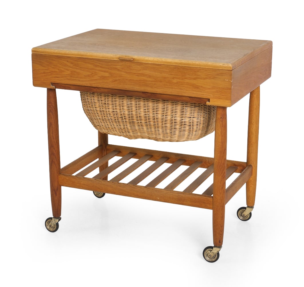 EJVIND A. JOHANSSON FOR FDB OAK SEWING TABLE: Model R101 oak sewing table designed by Ejvind A. Johansson for FDB mobler. Divided compartment under lid top. Wicker slide basket and lower slat shelf. On casters. Apparently unmarked. Denmark,