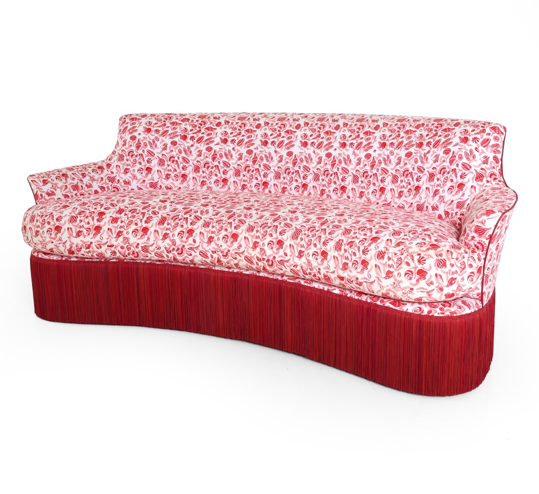 NAPOLEON III STYLE CURVED FRINGE SOFA: Three-seater sofa with red and white shell pattern to fabric. Red tassel fringe. Painted legs. 20th century. Dimensions: H 30.25" x W 75.5" x D 34" x SH 17.25". Condition: Scuffs and dings to legs.