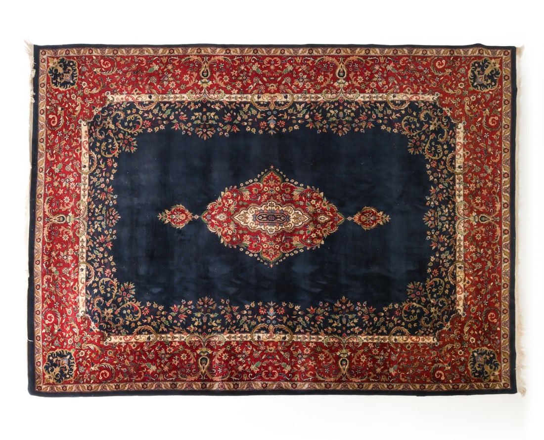 PERSIAN KERMAN HAND-KNOTED WOOL RUG: Featuring a deep navy blue central field and a intricate central medallion. Dimensions: H 148" x W 105" Condition: Wear consistent with age and use.